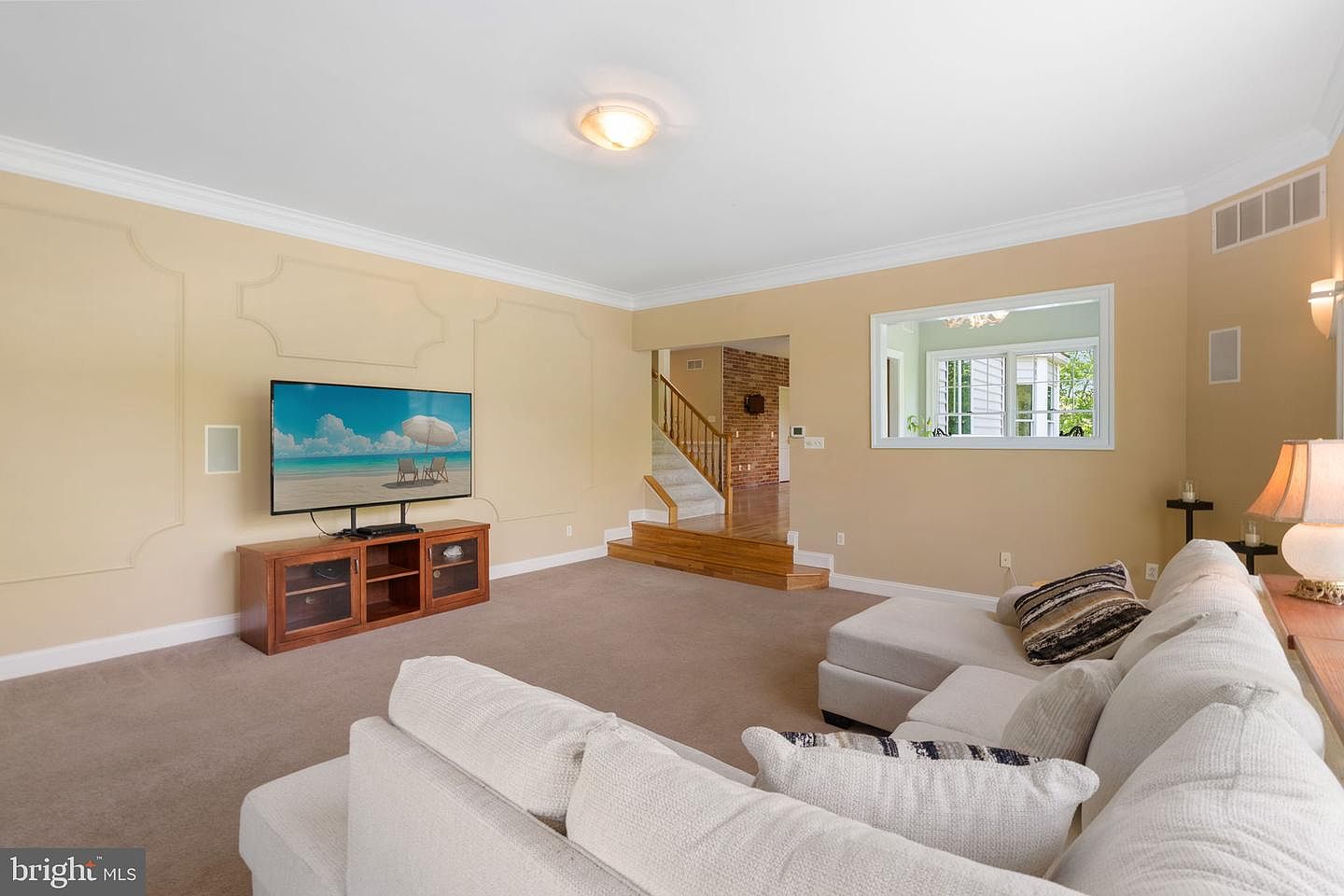 The family room opening to the back staircase and the brick stair landing, with the family television wall and wainscot millwork